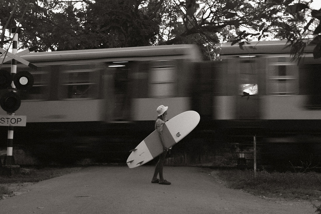 a man holding a surfboard walking down a street