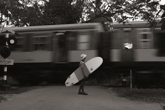 a man holding a surfboard walking down a street