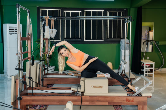 Woman does pilates exercises on a reformer machine.