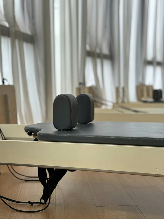Pilates reformer with padded headrest and straps.